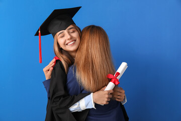 Happy female graduation student with her mother on color background