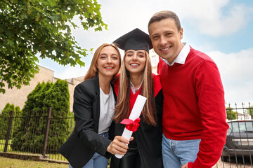 Happy young woman with her parents on graduation day