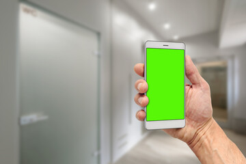 Man holding modern mobile device with launched smart home application and green mockup display