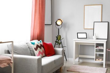Interior of light living room with sofa, lamp and modern workplace