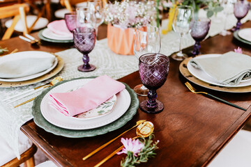 Table setup with flowers, glasses and plates on table decorated for Wedding Reception in terrace...