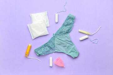 Menstrual pads, panties and tampons on purple background