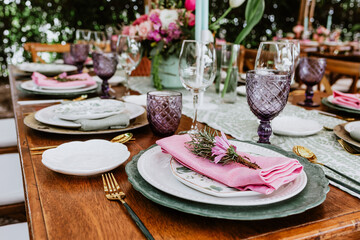 Table setup with flowers, glasses and plates on table decorated for Wedding Reception in terrace Latin America