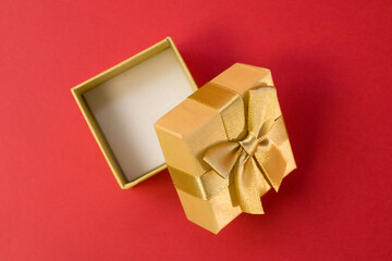 Open golden gift box with silk gold ribbon bow on bright pink background