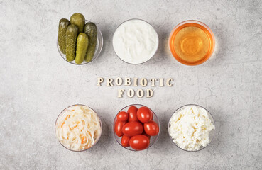 A variety of fermented foods for gut health. Bowls on a gray background. Cucumbers, tomatoes, sauerkraut, yogurt, cottage cheese, apple cider vinegar.