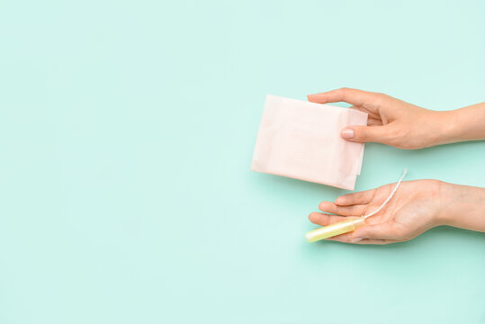 Female hands with menstrual pad and tampon on color background