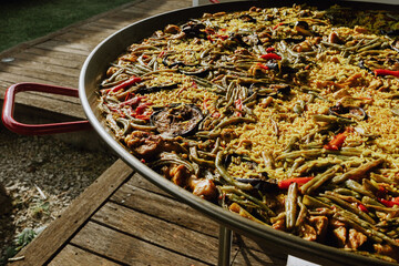 Process of preparing paella in a pan with chicken and vegetables and chef's hand seasoning and...