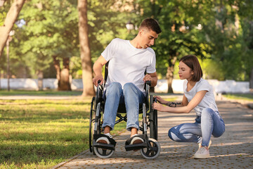 Young man with physical disability and his wife having problem with wheelchair in park