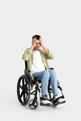 Obraz na płótnie Canvas Stressed young man in wheelchair on light background