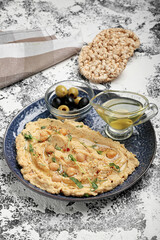 Plate with delicious hummus, olives and oil on color background