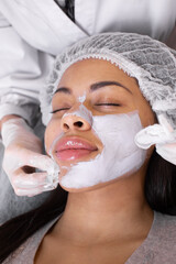 Application of cosmetology mask on the face of young african american woman. Procedure for face skin rejuvenation.Wellness relaxation concept.