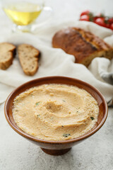 Bowl with delicious hummus on light background, closeup