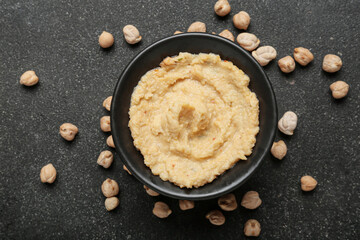Bowl with delicious hummus and chickpeas on dark background