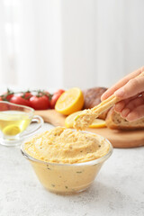 Woman eating delicious hummus on table, closeup