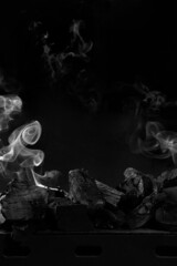 Extinguished coals on grill barbecue on black background with white smoke