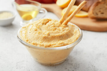 Bowl with delicious hummus and crackers on light background, closeup