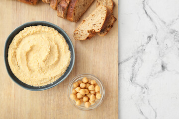 Bowl with delicious hummus and bread on light background