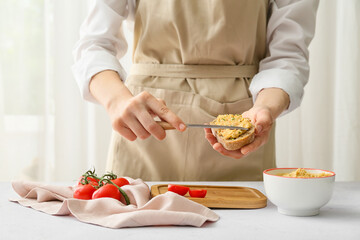 Woman making delicious sandwich with hummus at table