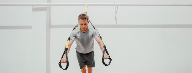Fitness man training core abs muscles doing plank pushups balance workout on suspension cables at...