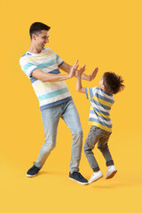 Dancing man and his little son on color background