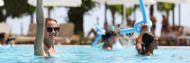 Young women during water aerobics classes in hotel pool closeup