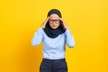 Portrait of stressed young Asian woman touching his temples and having headache isolated on yellow...