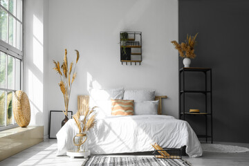 Interior of modern bedroom with dry reeds in vases