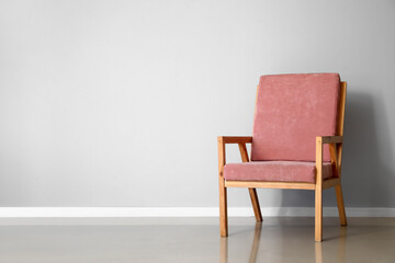 Fototapeta na wymiar Pink wooden armchair near light wall
