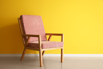 Pink wooden armchair near color wall