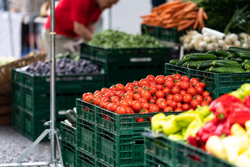 Red tomatoes on the open space market in box between another vegetables.