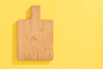 Handmade cherry wood wooden cutting board on orange yellow background.