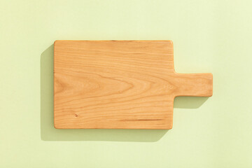 Handmade cherry wood wooden cutting board on light green background.