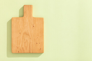 Handmade cherry wood wooden cutting board on light green background.