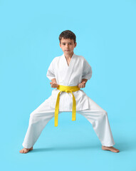 Little boy practicing karate on color background