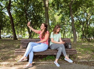 Divided separated friendship and life online, two young women girls each one into hers own online world and life, concept of living online instead real life watching content on social media networks