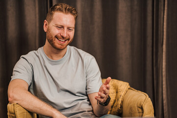 Portrait of man watching tv or online video and reacting or listening to a friend and commentating