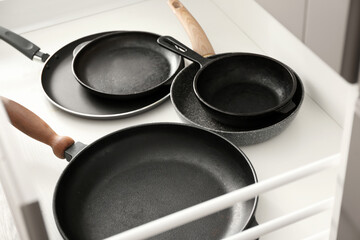 Different frying pans in open kitchen drawer, closeup
