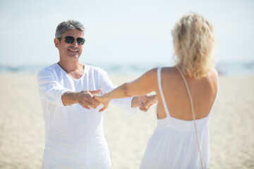 senior couple dancing on the beach on a sunny day