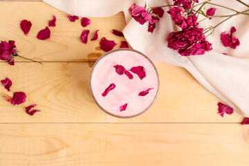 Glass of tasty rose latte on wooden background