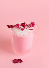 Cup of tasty rose latte on color background