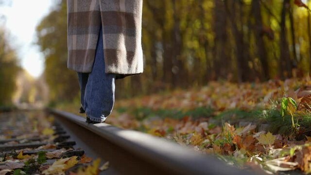 lonely woman is walking over tram rail in sunny fall day, closeup of feet