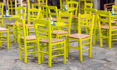 Fototapeta na wymiar Cafe bar open air. Empty seats on cobblestone street background, Areopoli, Mani Greece