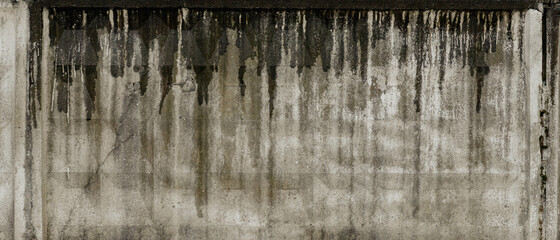 Texture of grey concrete wall with dark water and oil marks running vertically down and many marks...
