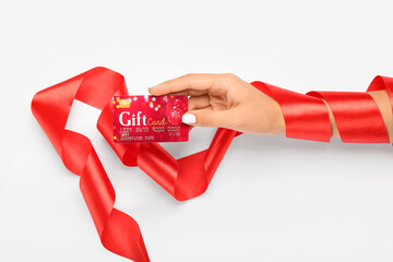 Woman with gift card and red ribbon on white background