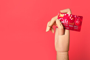Wooden hand with gift card on red background