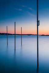 Poles standing in water at sunset