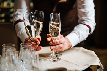 Sommelier man picks up elegant glasses of champagne, standing in a row on the serving table