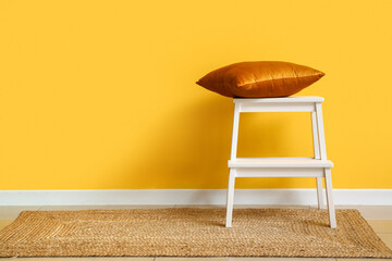 White step stool with pillow near yellow wall
