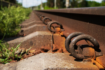   Railway tracks amidst trees. Rails and sleepers close up. Selective focus.