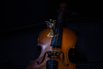 An old violin in a case and a glass toy of the Muse with a violin. Dark background. Selective focus